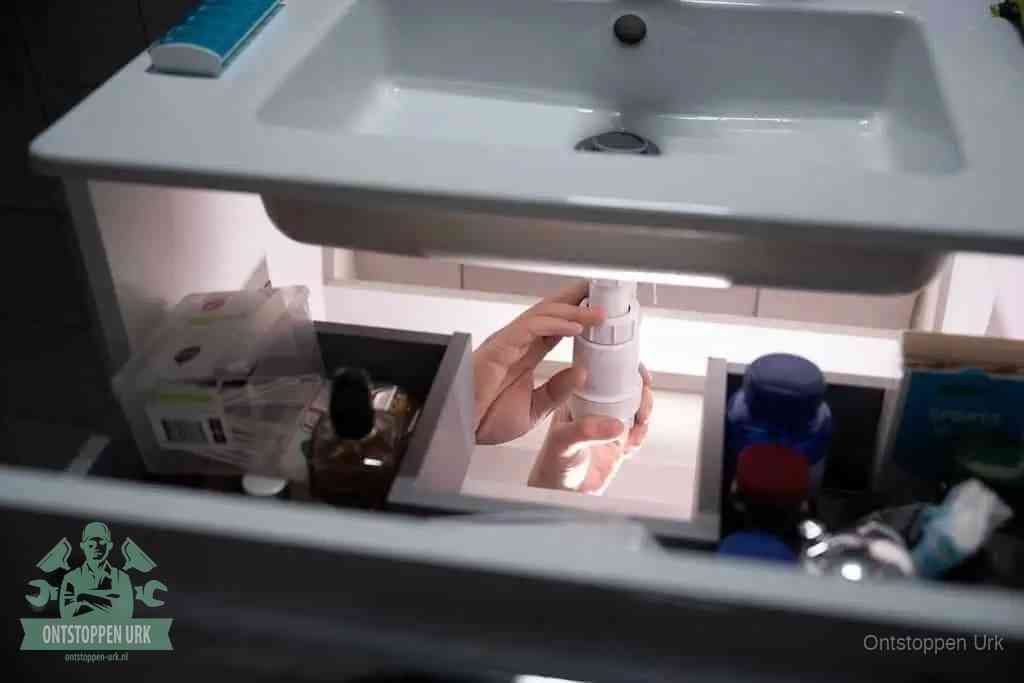 Een pompfles met zeep boven een wastafel, de heet water en afwasmiddel-methode om een vetprop in de afvoer los te maken in Urk