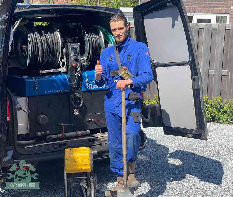 Een monteur bij de werkbus met grote hogedruk-slanghaspels, apparatuur voor hardnekkige afvoerverstoppingen in Urk
