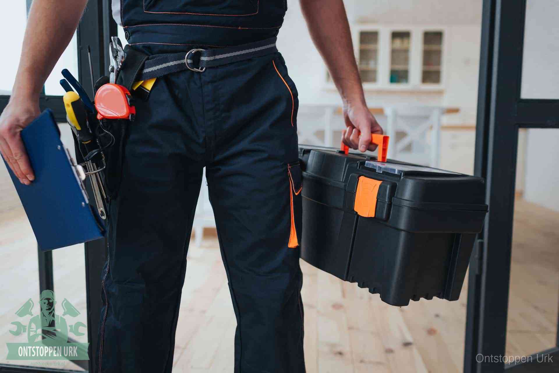 Een monteur met gereedschapsriem en klembord in een keuken, klaar om een transparante prijs voor het gootsteen ontstoppen in Urk te geven