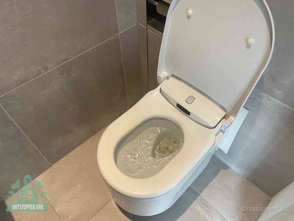 Een toiletpot vol troebel water met drijvend papier en restanten, de meest voorkomende oorzaak van een verstopte wc in Urk