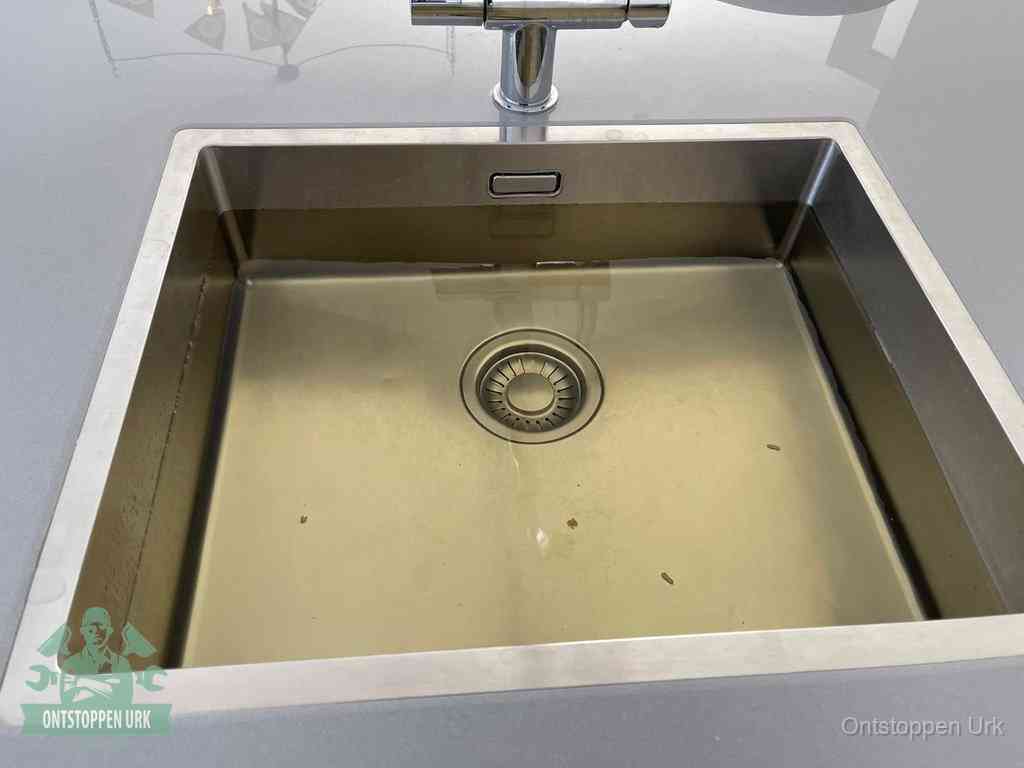 Stilstaand water in een rvs spoelbak dat niet wegloopt, een duidelijk signaal van een gootsteenverstopping in Urk