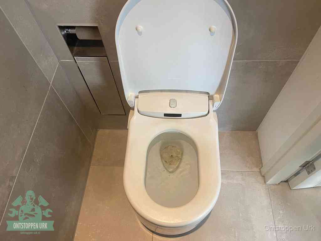 Een wit hangtoilet waarin een prop wc-papier op het water blijft drijven, een duidelijk signaal van een verstopte wc in Urk