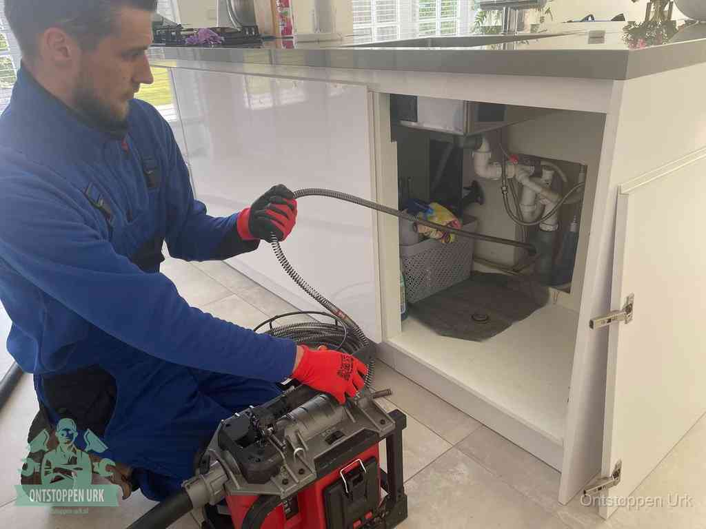 Een monteur reinigt de keukenafvoer grondig met een veermachine om terugkerende gootsteenverstoppingen te voorkomen in Urk