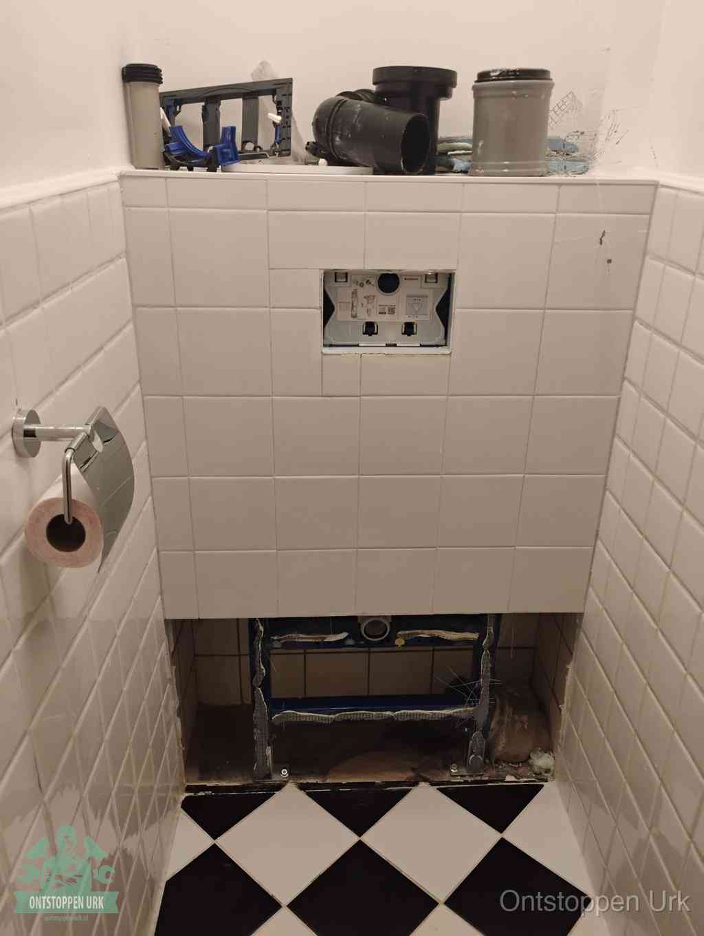 Een toiletruimte waar het hangtoilet en de inbouwreservoir-onderdelen zijn vrijgelegd voor onderhoud, periodiek nazicht voorkomt een wc-verstopping in Urk